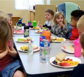 Cheerful Elementary School Children Enjoying Lunch at Classroom Table Clipart Scene
